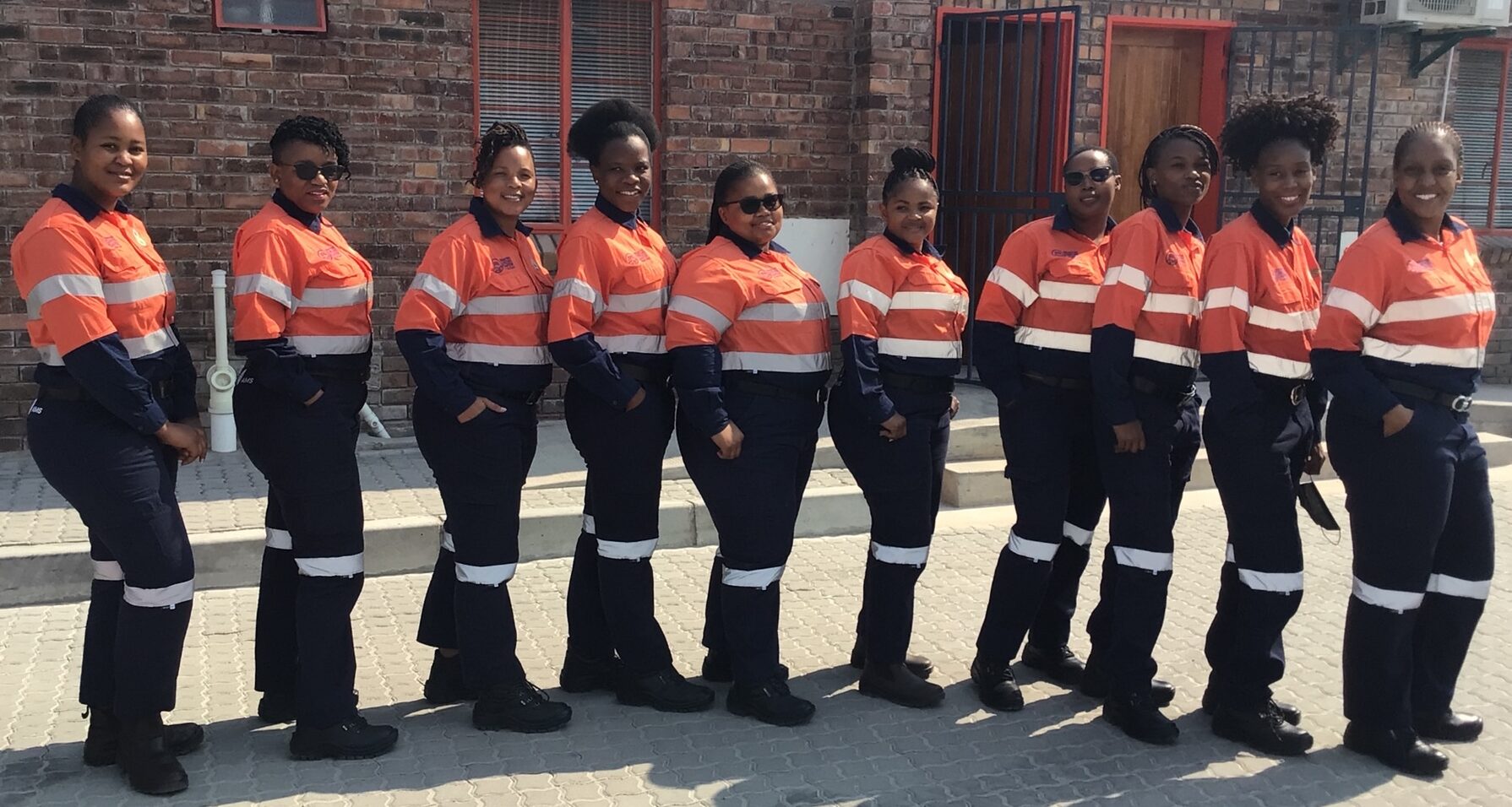 Botswana ten female truck drivers who graduated from Perenti training centre, smiling and standing in a row at 45 degrees turn